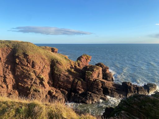 Views looking out to sea of cliffs and clouds in the sky